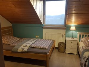 Schlafzimmer mit zwei Einzelbetten, Schrank und Tisch. Zum Schlafzimmer gehört eine separate Toilette mit Waschbecken.