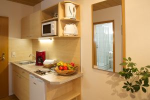 Kleine Küchenzeile mit Ceranfeldkochfeld, Kühlschrank mit Gefrierfach, Teller, Tassen Gläser, Besteck, Töpfe, Kochutensilien, Kaffeemaschine, Wasserkocher, Toaster, Geschirrtücher