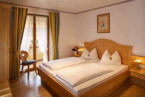 Schlafzimmer mit Doppelbett, Kleiderschrank und Nachttisch, teilweise mit Kofferbock